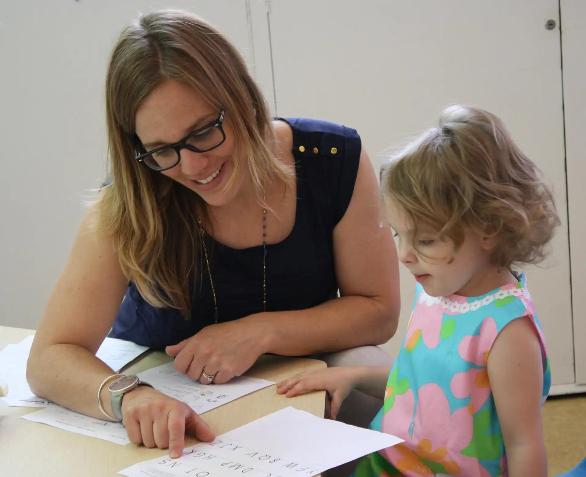 A teacher helps a student with an alphabet worksheet