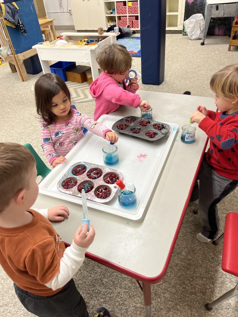 A group of students sit at a desk investigating how room-temperature water interacts with ice cubes