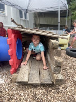 A student plays outside in a fort made of wood